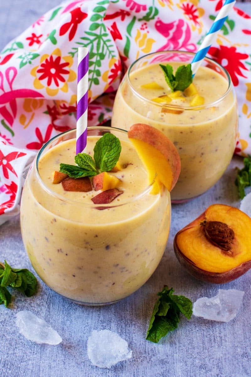 Two glasses of Peach Smoothie topped with mint leaves.