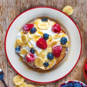 A plate of Banana Pancakes topped with cream and berries