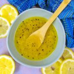 Lemon vinaigrette in a bowl with a small wooden spoon.