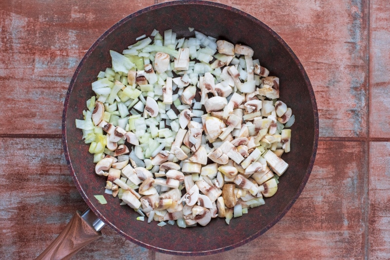 Chopped onion, mushrooms and garlic in a frying pan.