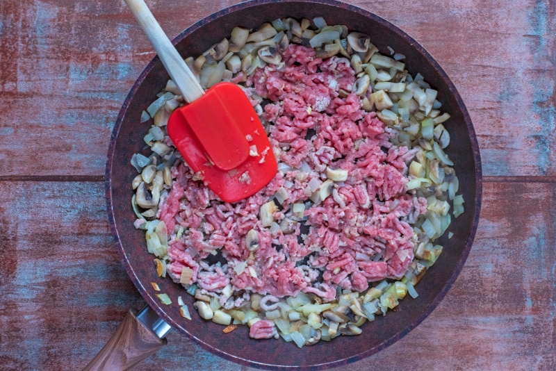 Chopped onion, mushrooms, ground turkey and garlic in a frying pan.