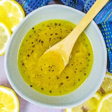 Lemon vinaigrette in a bowl with a small wooden spoon.