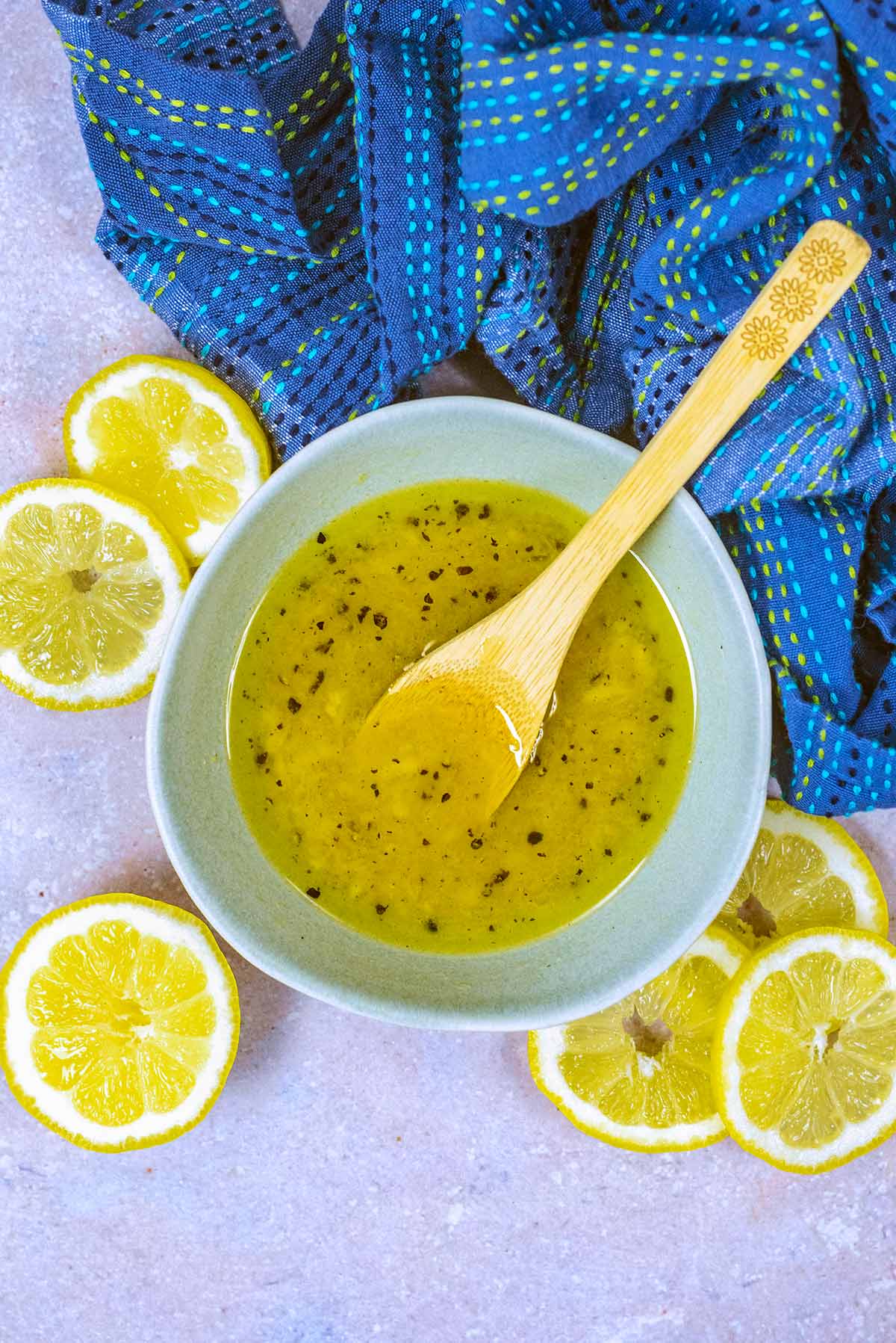 A bowl of yellow dressing surrounded by lemon slices.