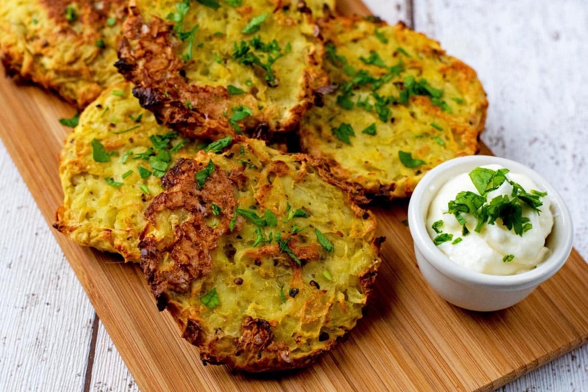 Hash browns on a wooden board with a small pot of dip.