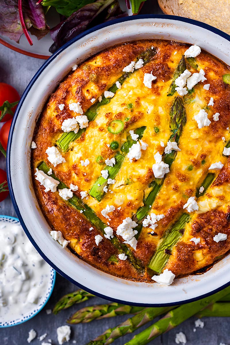 Feta and Asparagus Frittata in a dish next to some asparagus spears