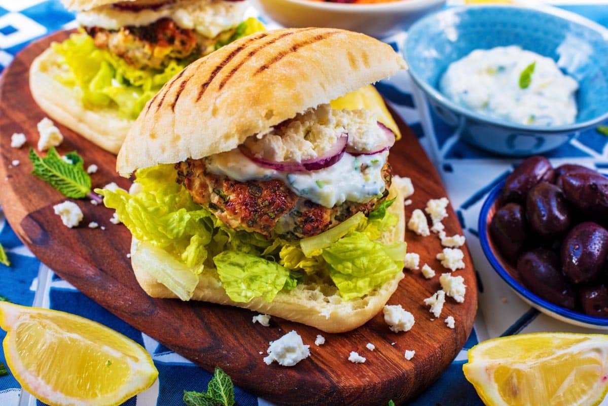 Greek Turkey Burgers on a wooden serving board.