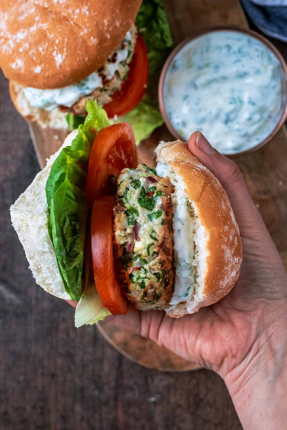 A hand holding a thick turkey burger in a bun.
