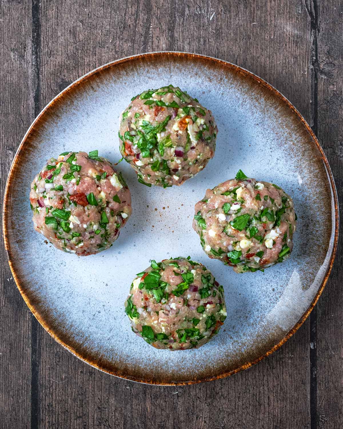 Four large burger patties on a plate.