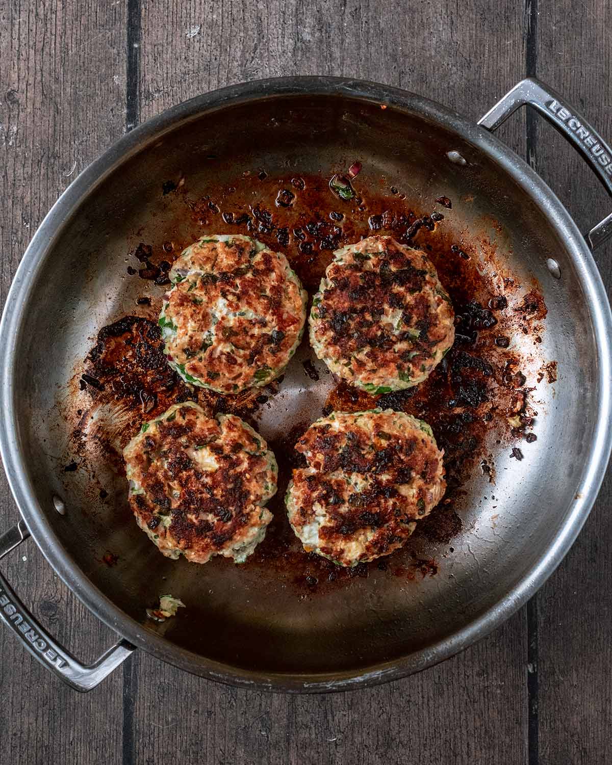 Four cooked burgers in the pan.