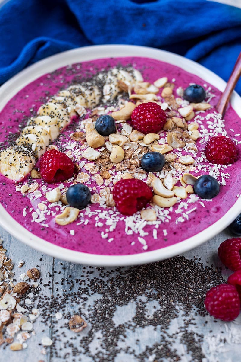a bowl full of purple smoothie with a small wooden spoon.
