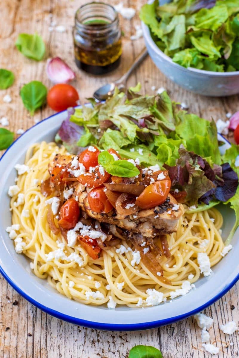 Chicken and vegetables on top of spaghetti.