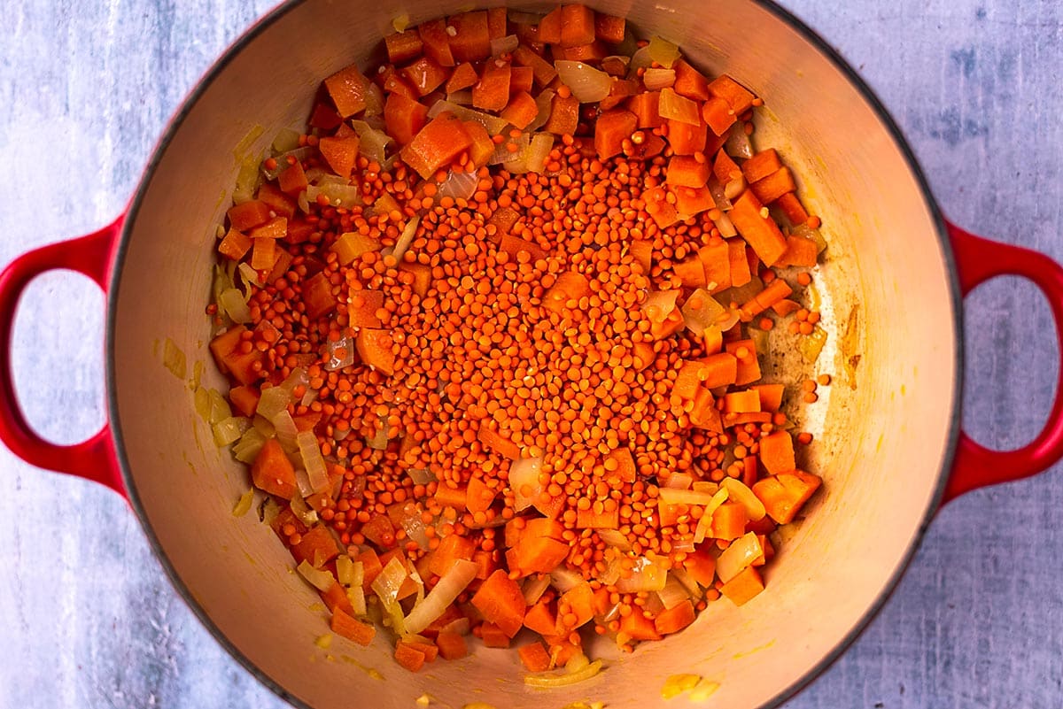 Carrots, onions and red lentils cooking in a large pot.