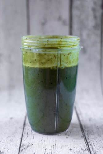 A blender jug containing a green smoothie