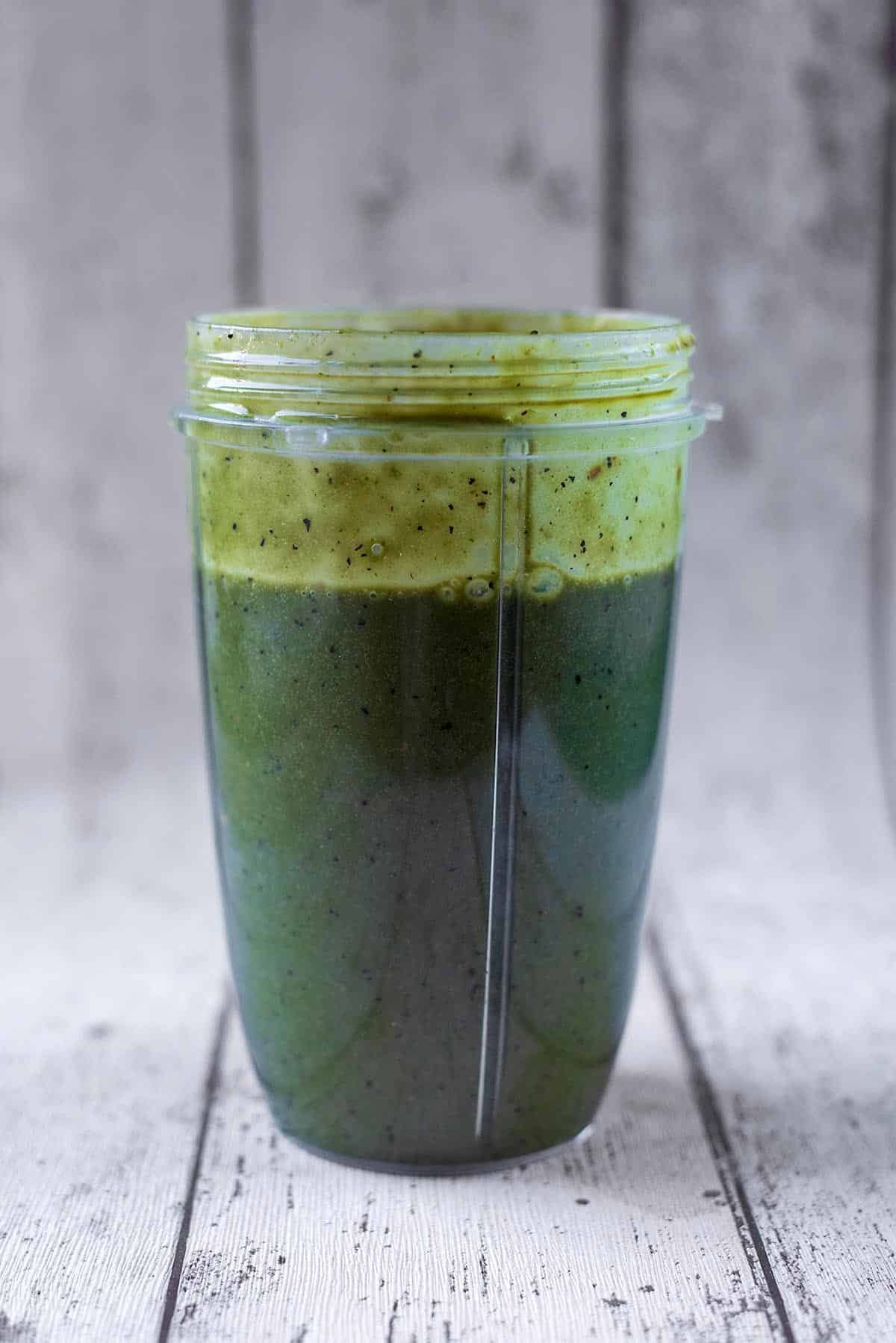 A blender jug containing a green smoothie.