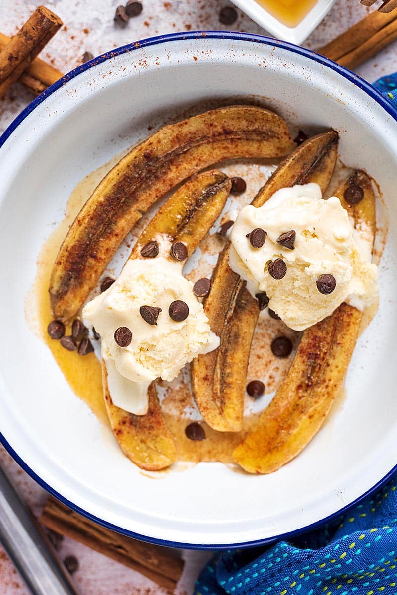 A round baking dish containing Honey Baked Bananas, Ice cream and chocolate chips.