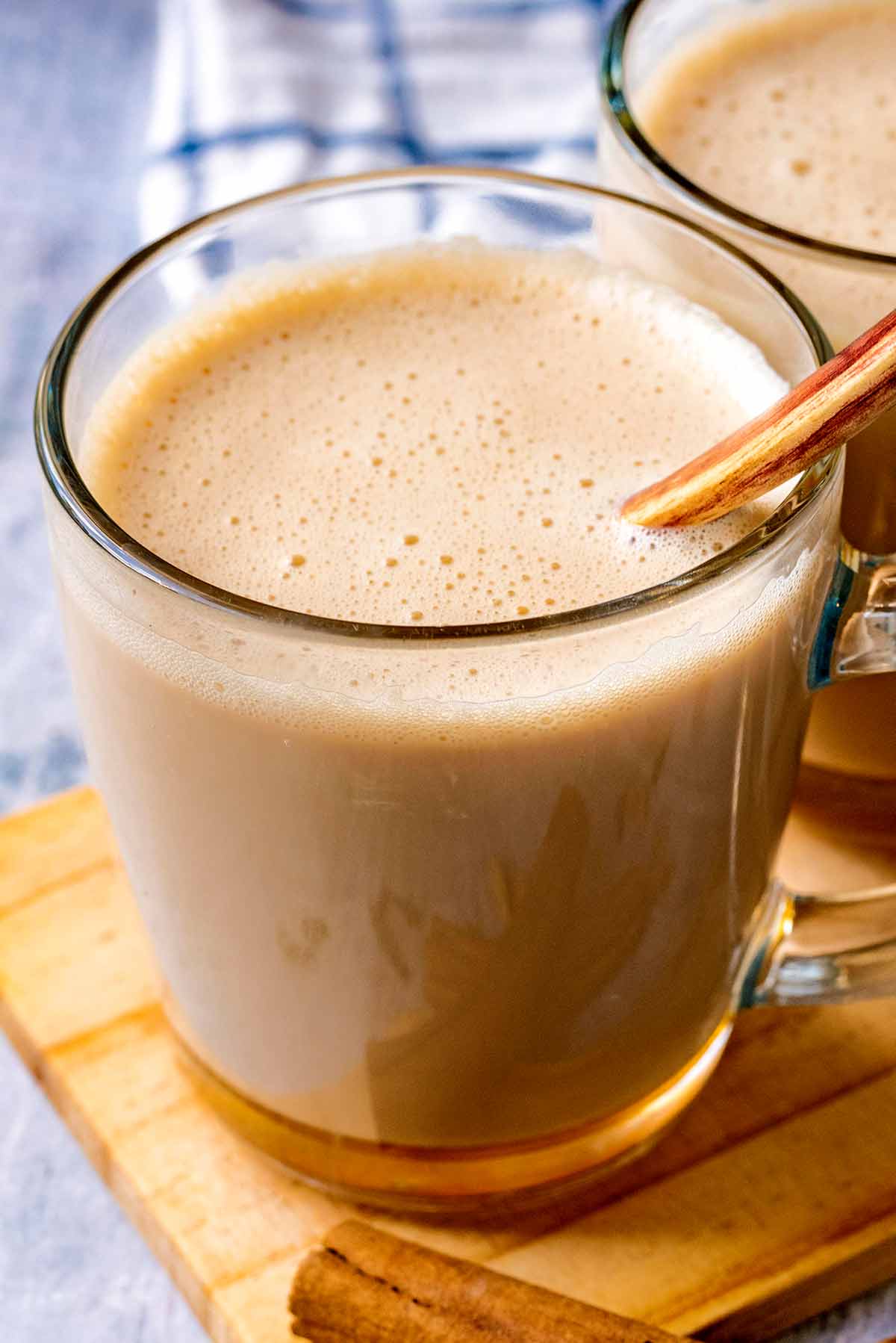 A glass of frothy latte with a spoon in it.
