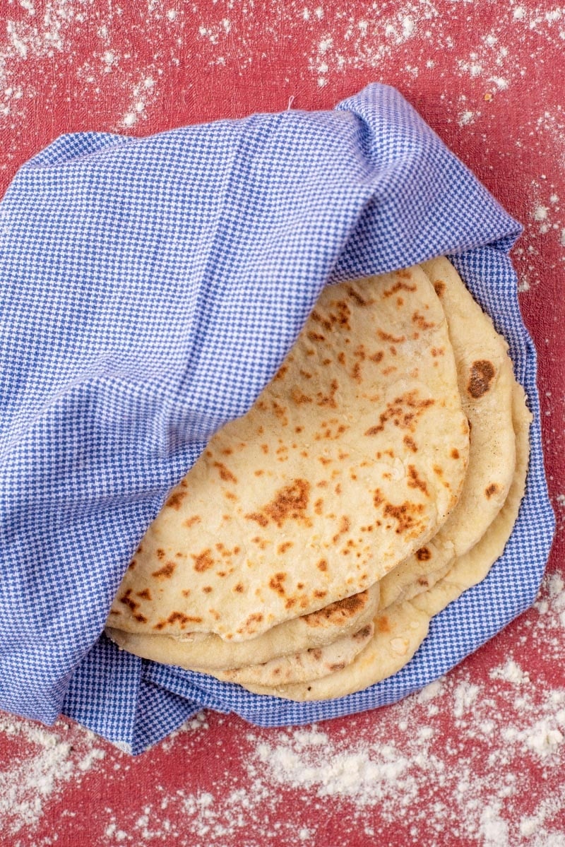 Four flatbreads wrapped in a blue towel.