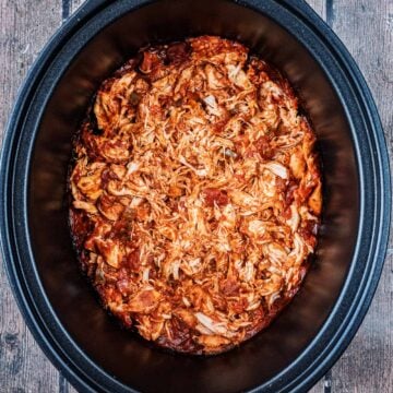 Slow cooker salsa chicken in a black slow cooker pot.