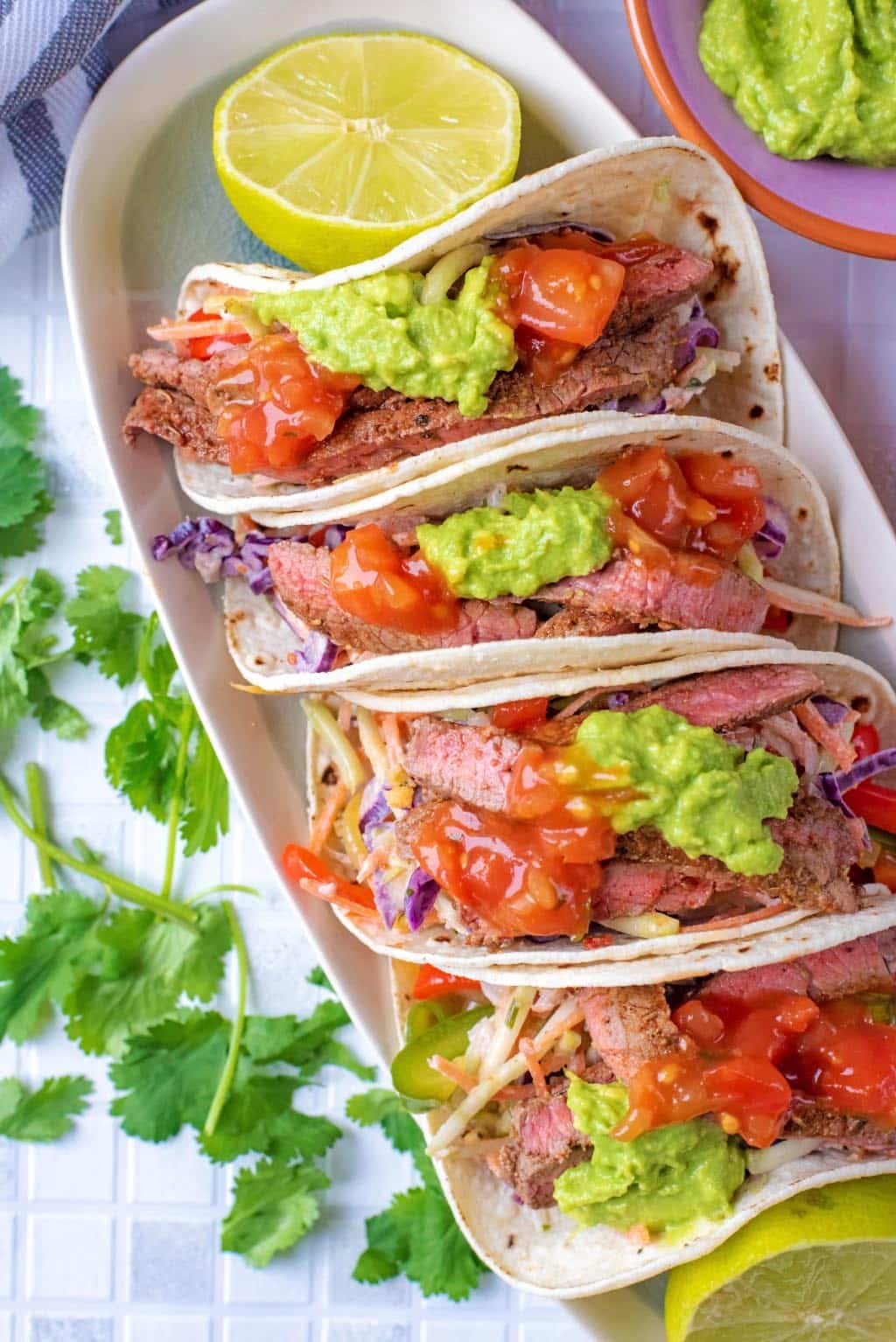 Four meat tacos with lime halves.