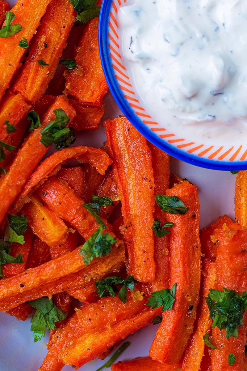Carrot fries on a plate topped with chopped herbs.