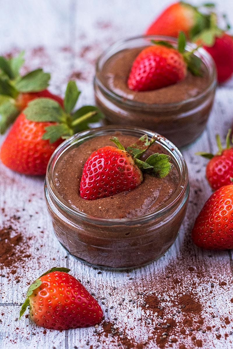 Chocolate pudding in a glass pot topped with half a strawberry.