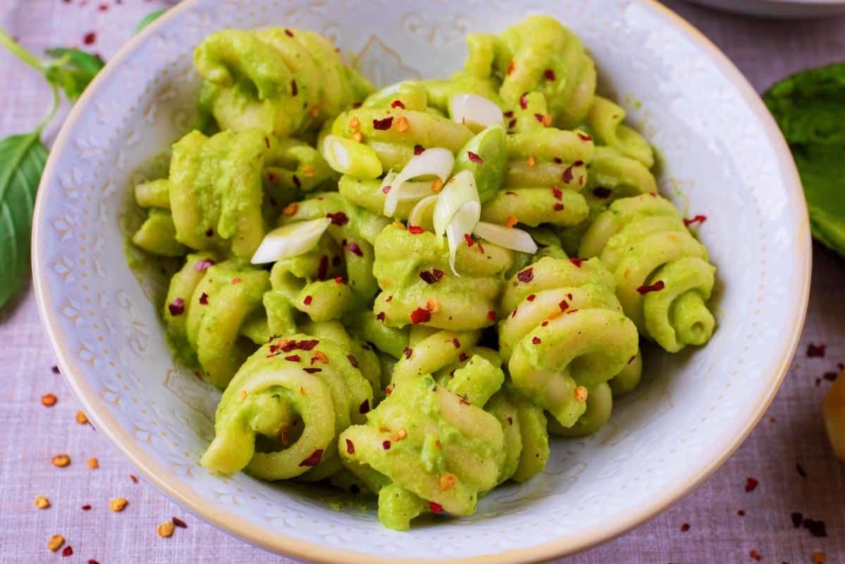 A bowl of Creamy Avocado Pasta with chilli flakes sprinkled on top.
