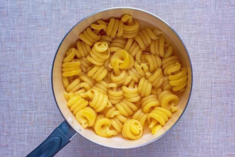 Pasta spirals cooking in a saucepan.