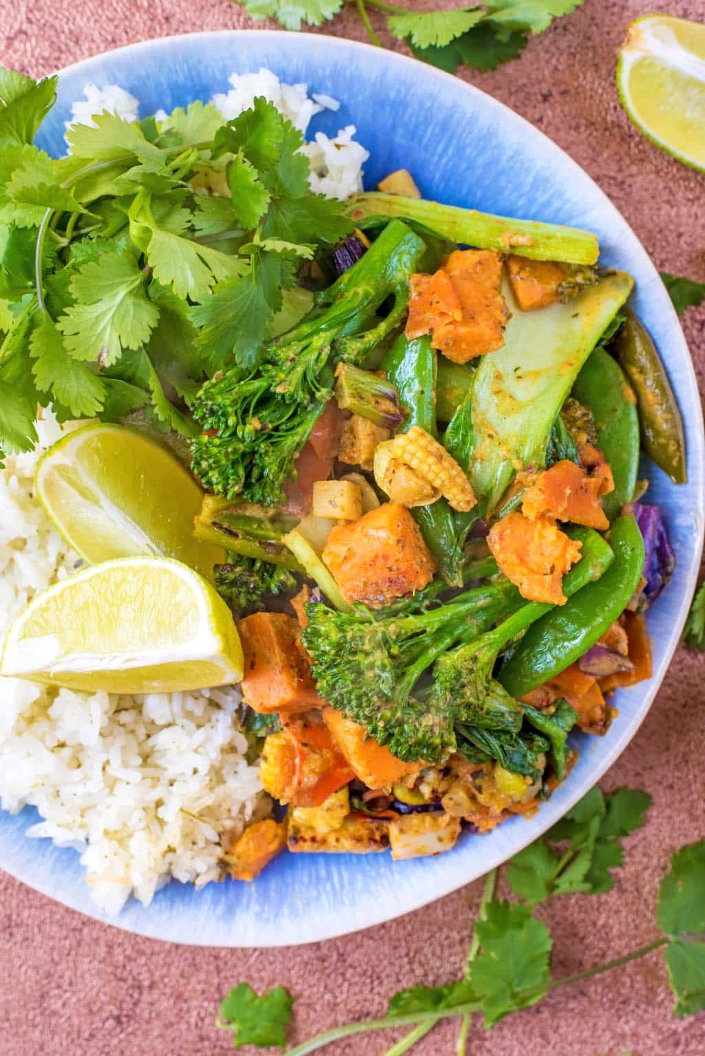 A plate of Thai Green Curry, rice and lime wedges.