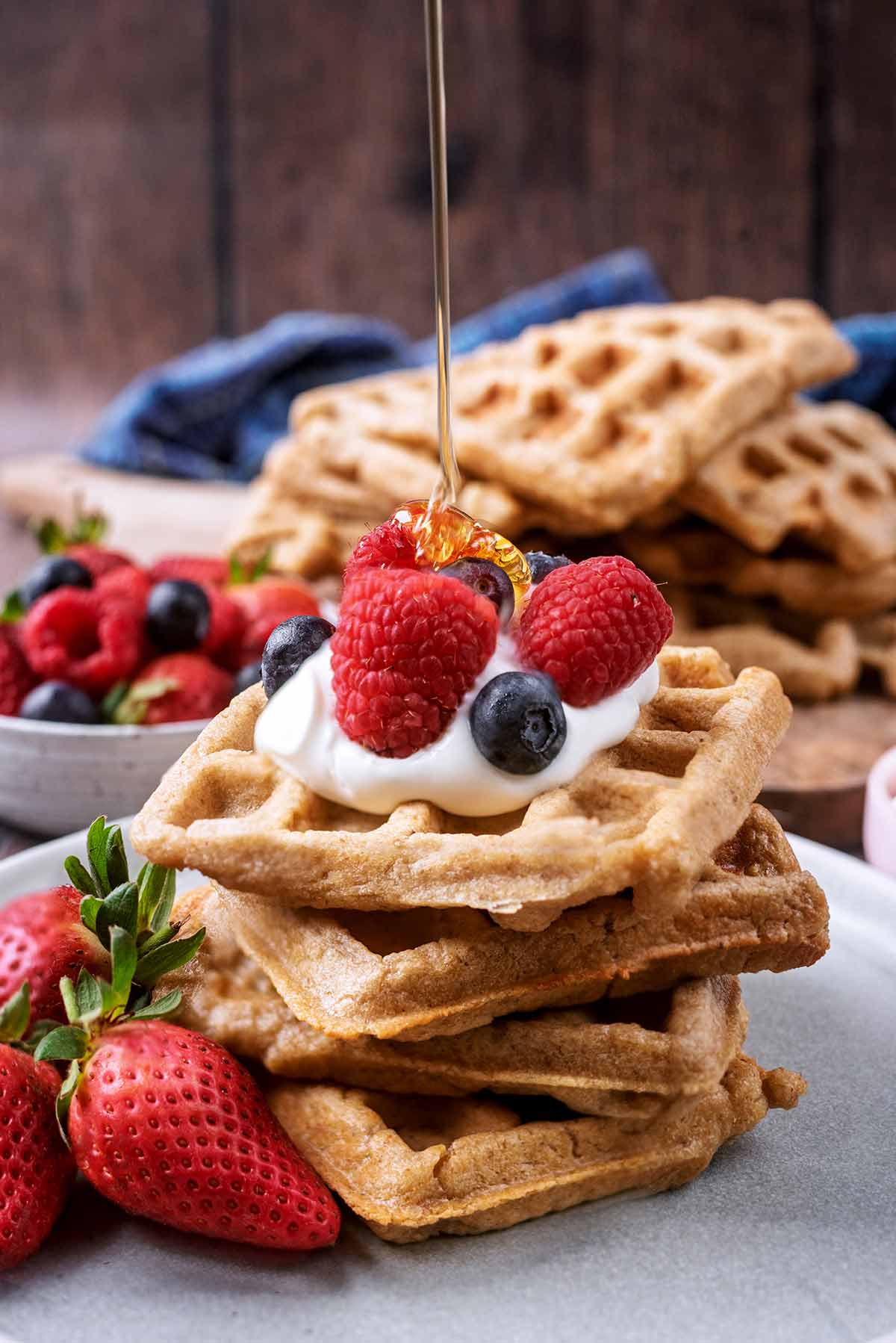 A stack of waffles with honey being drizzled onto them.