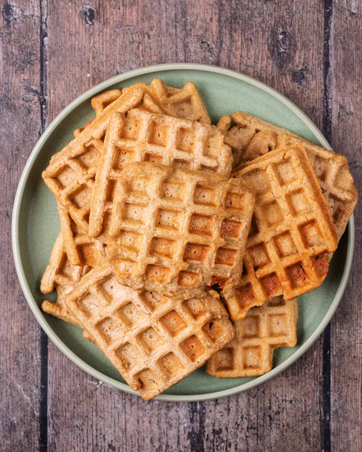 A green plate with lots of waffles on it.