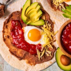 Huevos Rancheros next to an avocado half and bowl of salsa