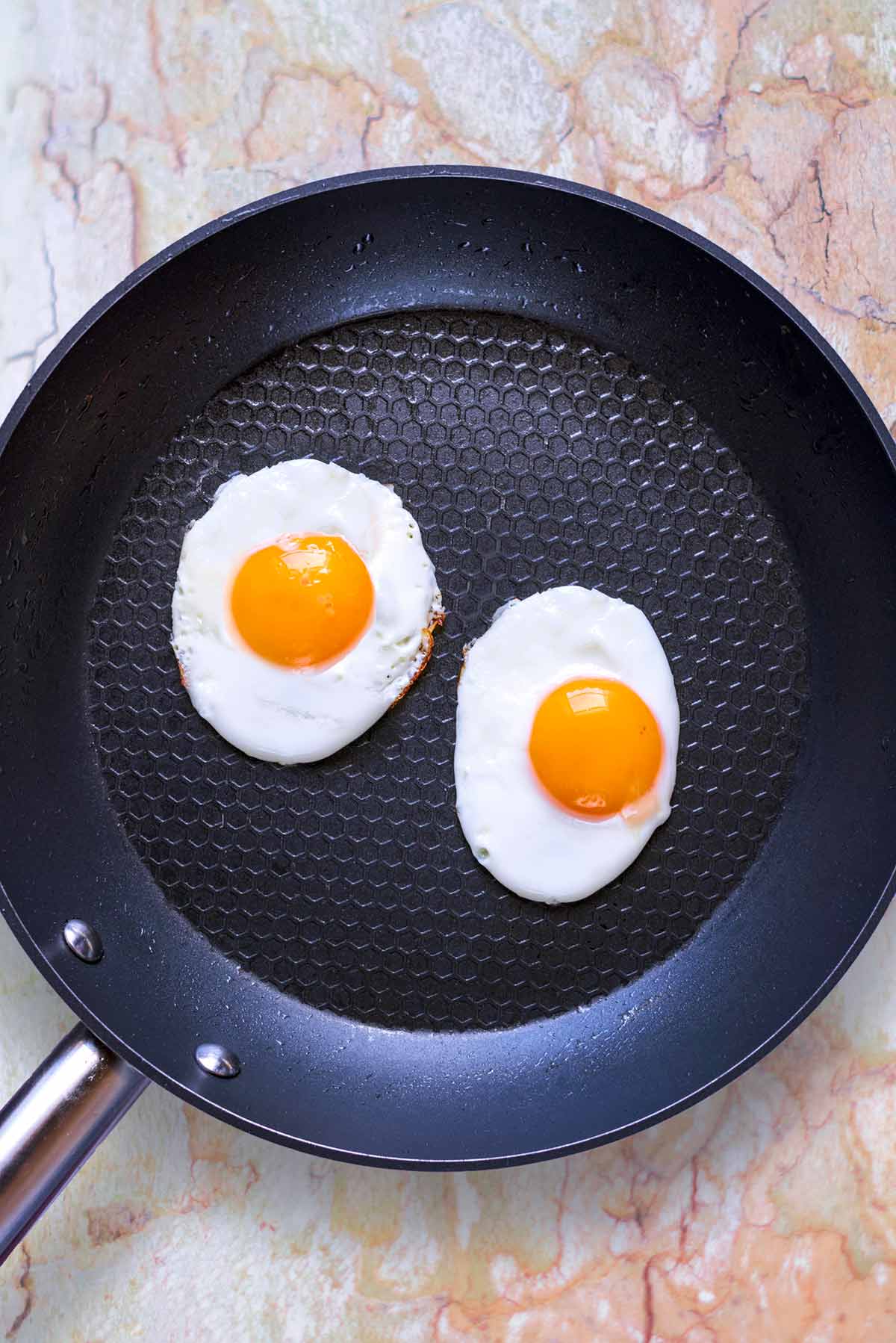 A frying pan with two fried eggs in it.