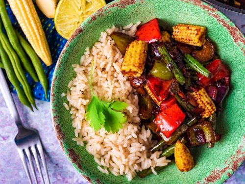 Vegetable Teriyaki and rice in a green bowl next to a pan of more teriyaki