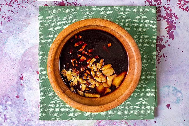 A small wooden bowl containing a teriyaki sauce.