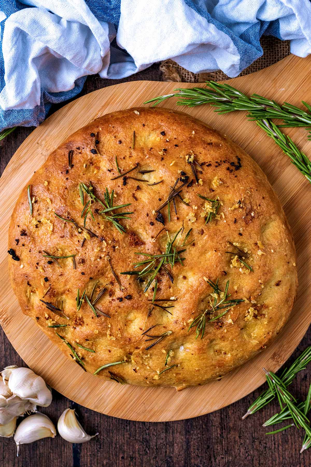 A round focaccia bread on a wooden serving board.