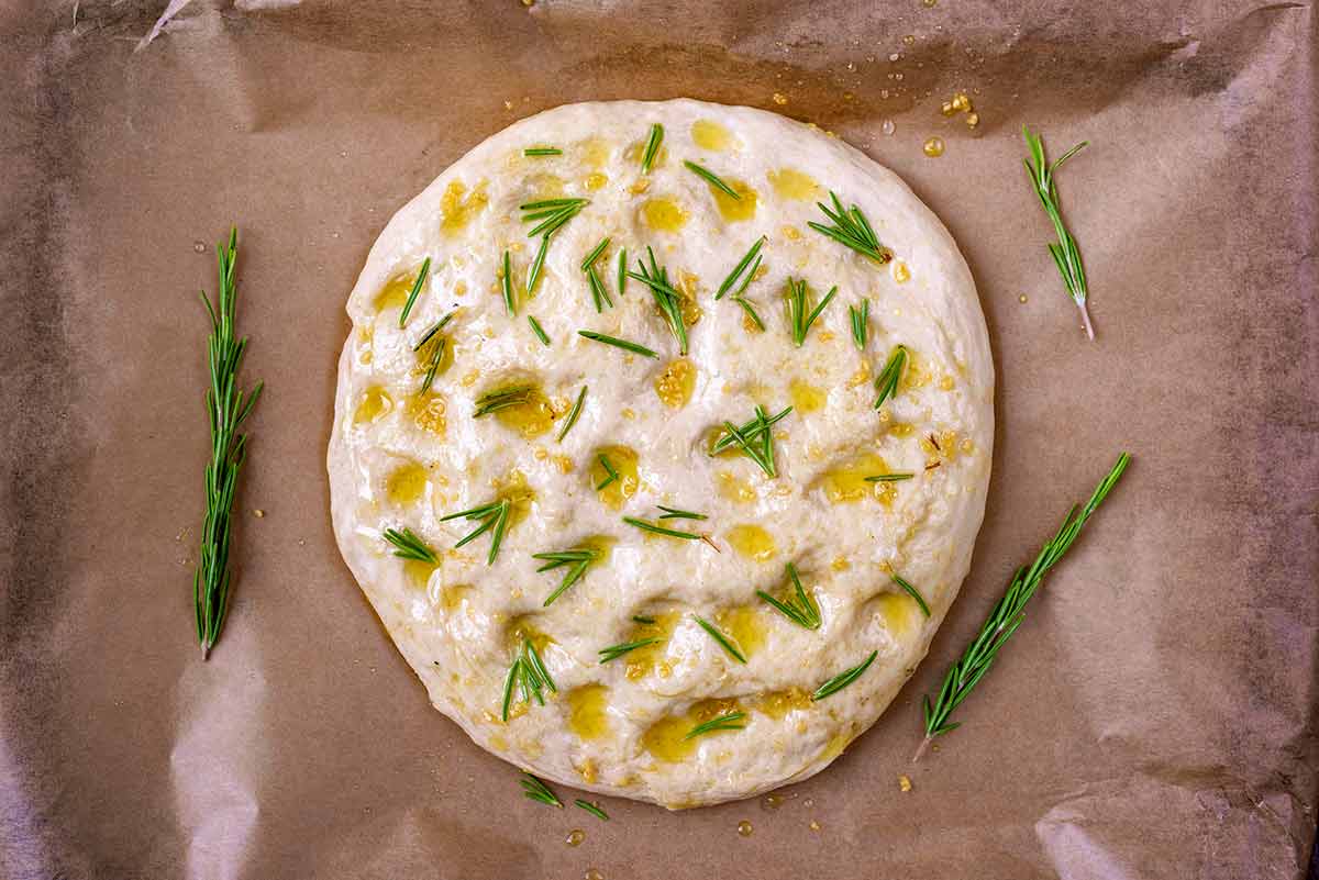 The dough brushed with oil and rosemary leaves added on top.