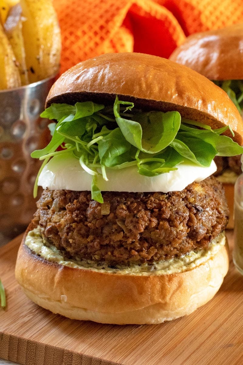 A quorn pesto burger in a brioche bun. Orange towel in the background.