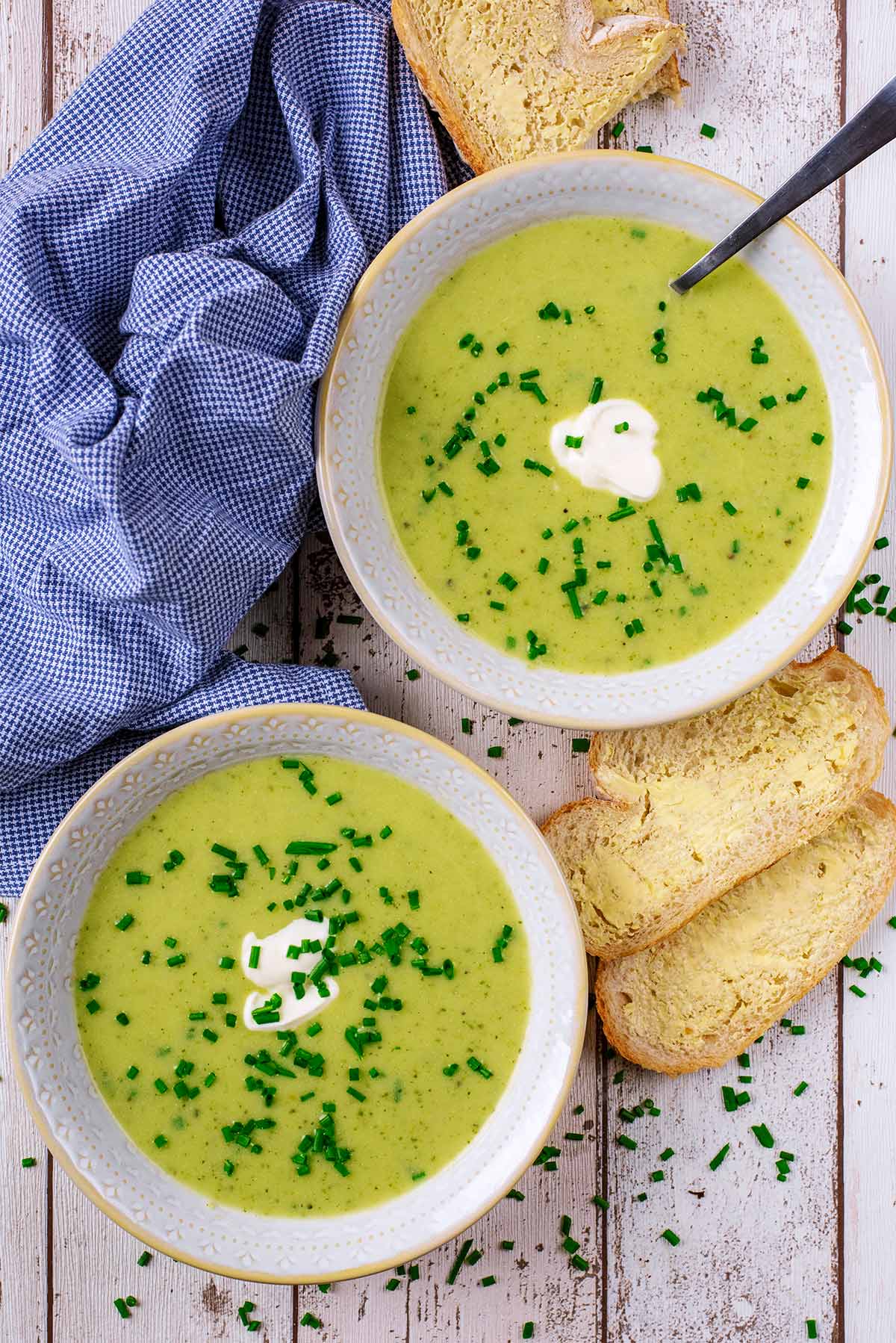 Two bowls of courgette soup with some buttered bread.