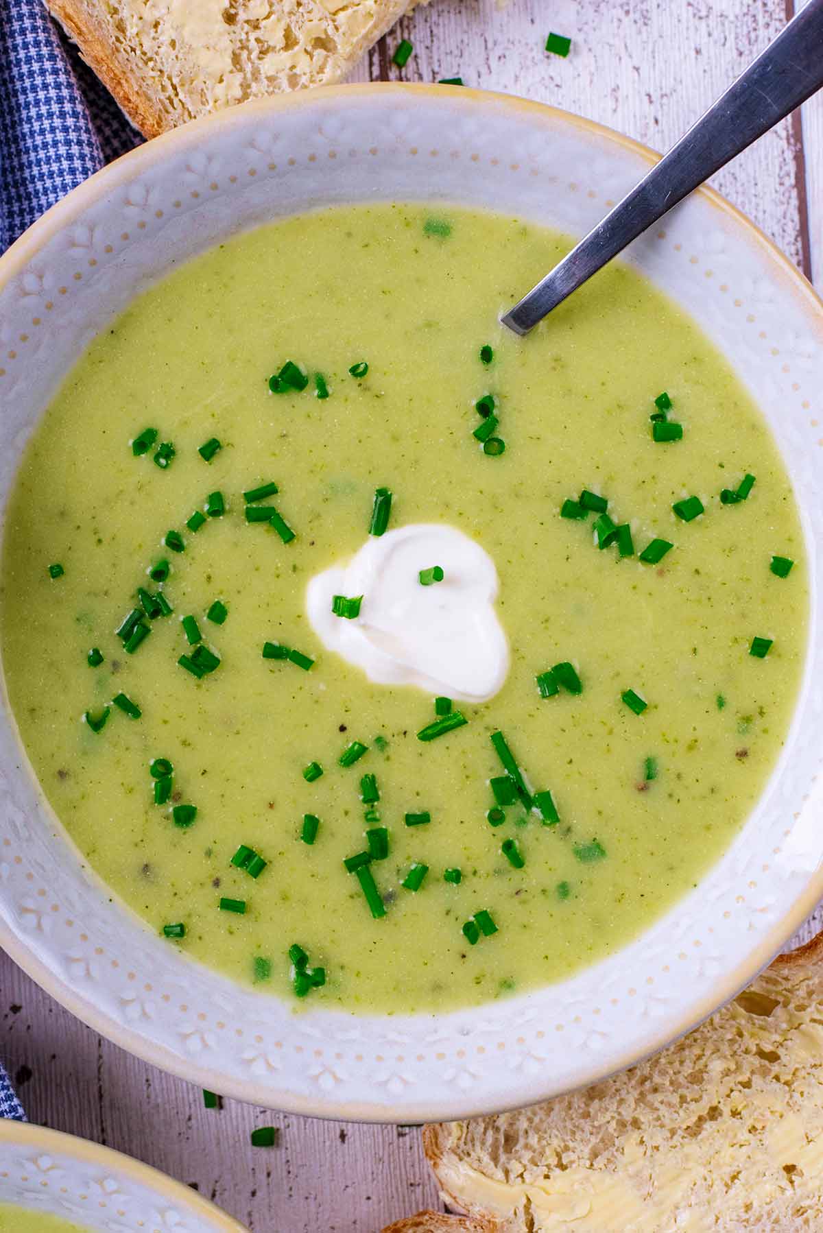 Courgette soup with a dollop of cream and a spoon.