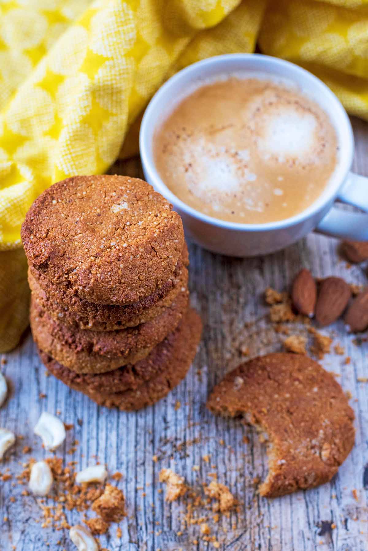 Gingernuts next to a cup of coffee and a yellow towel.