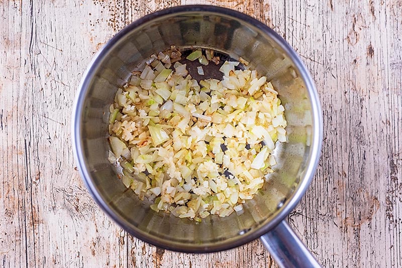 A saucepan with chopped onions and minced garlic.