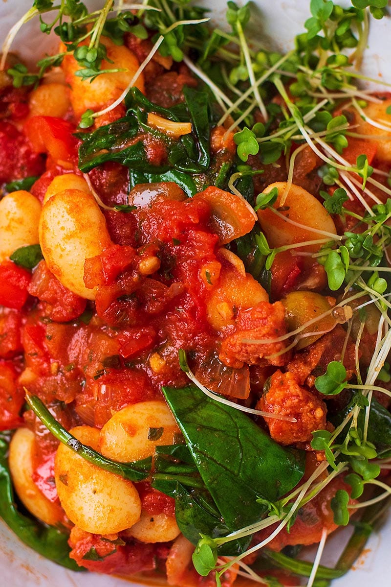 A stew of beans, chorizo and peppers mixed with wilted spinach and cress.