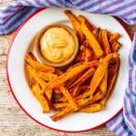 Baked Sweet Potato Fries on a white plate with a small bowl of dip.