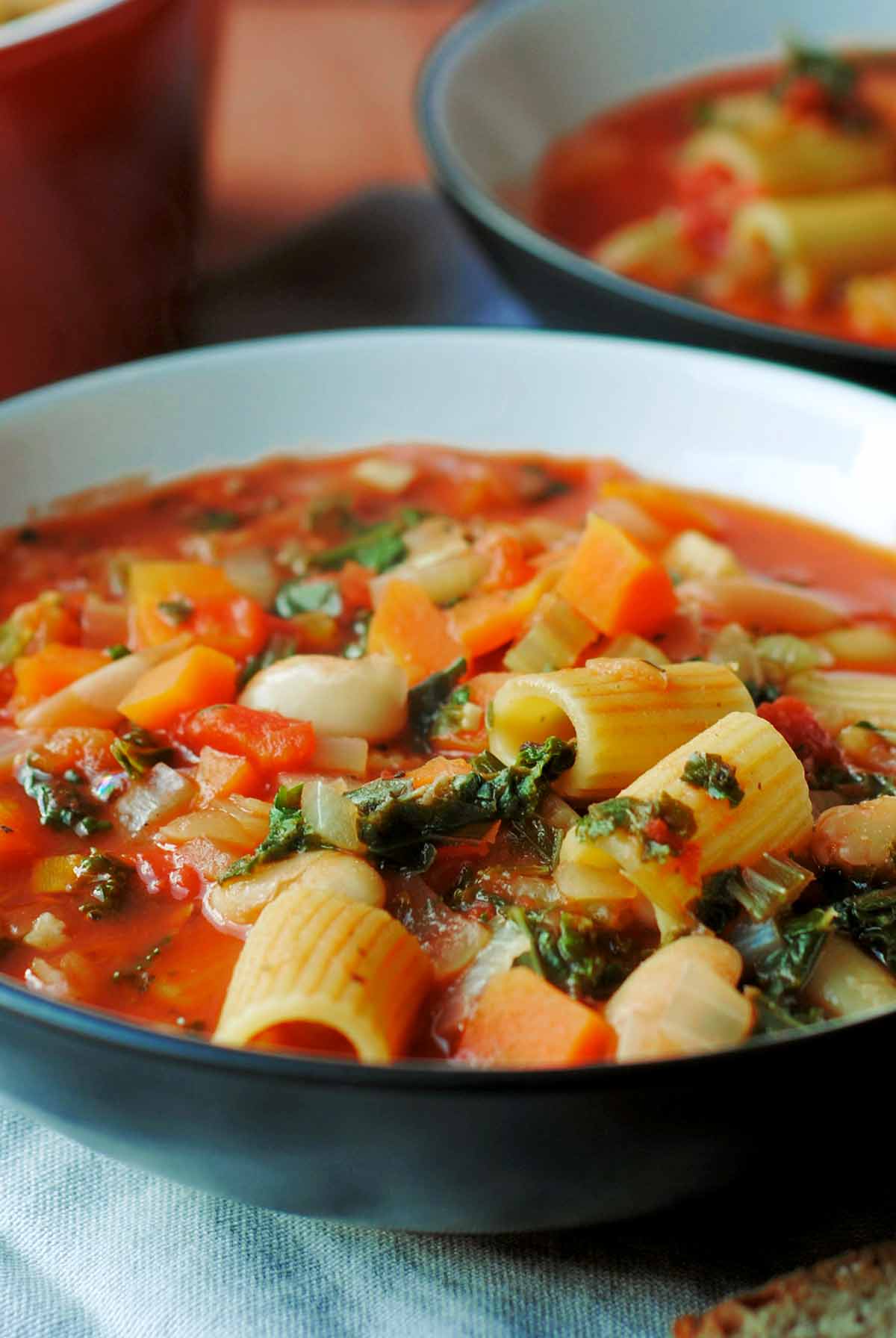 Pasta and vegetable soup in a shallow black bowl.