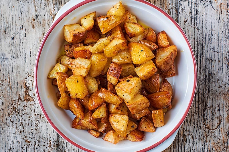 A bowl full of cooked cubes of potato.