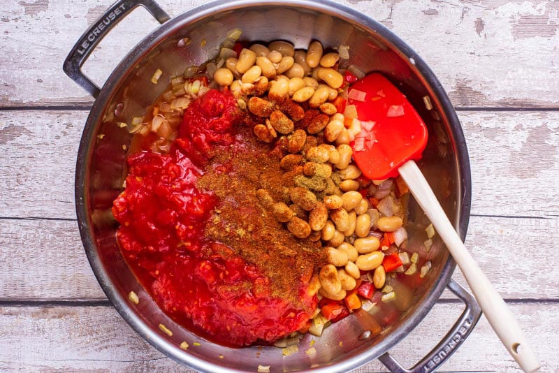 A large pan containing tomatoes, beans and spices.