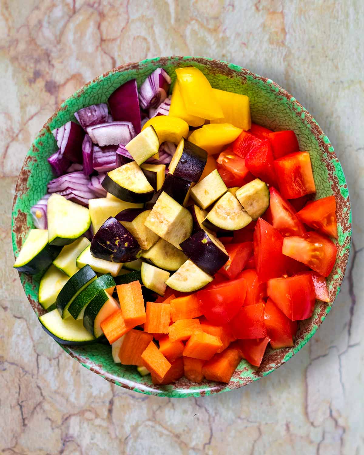 A green bowl full of chopped vegetables.