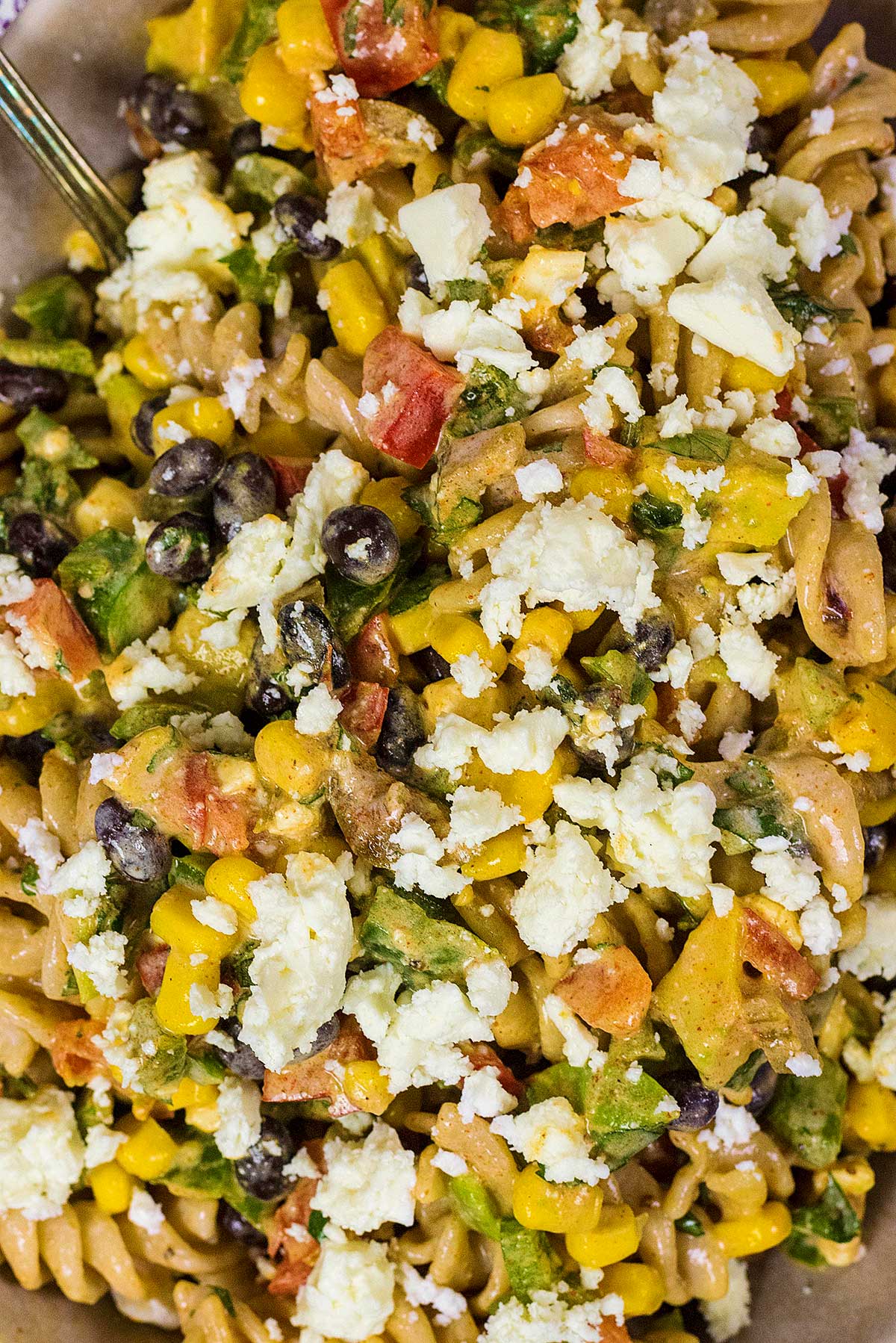 Cooked pasta mixed with corn, black beans, chopped peppers and crumbled feta.