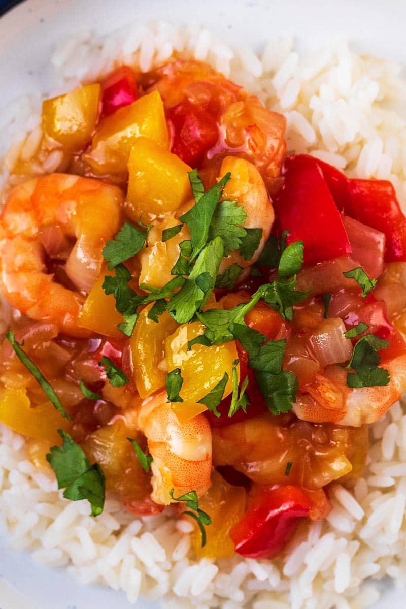 Sweet and sour shrimp topped with cilantro leaves on a bed of rice