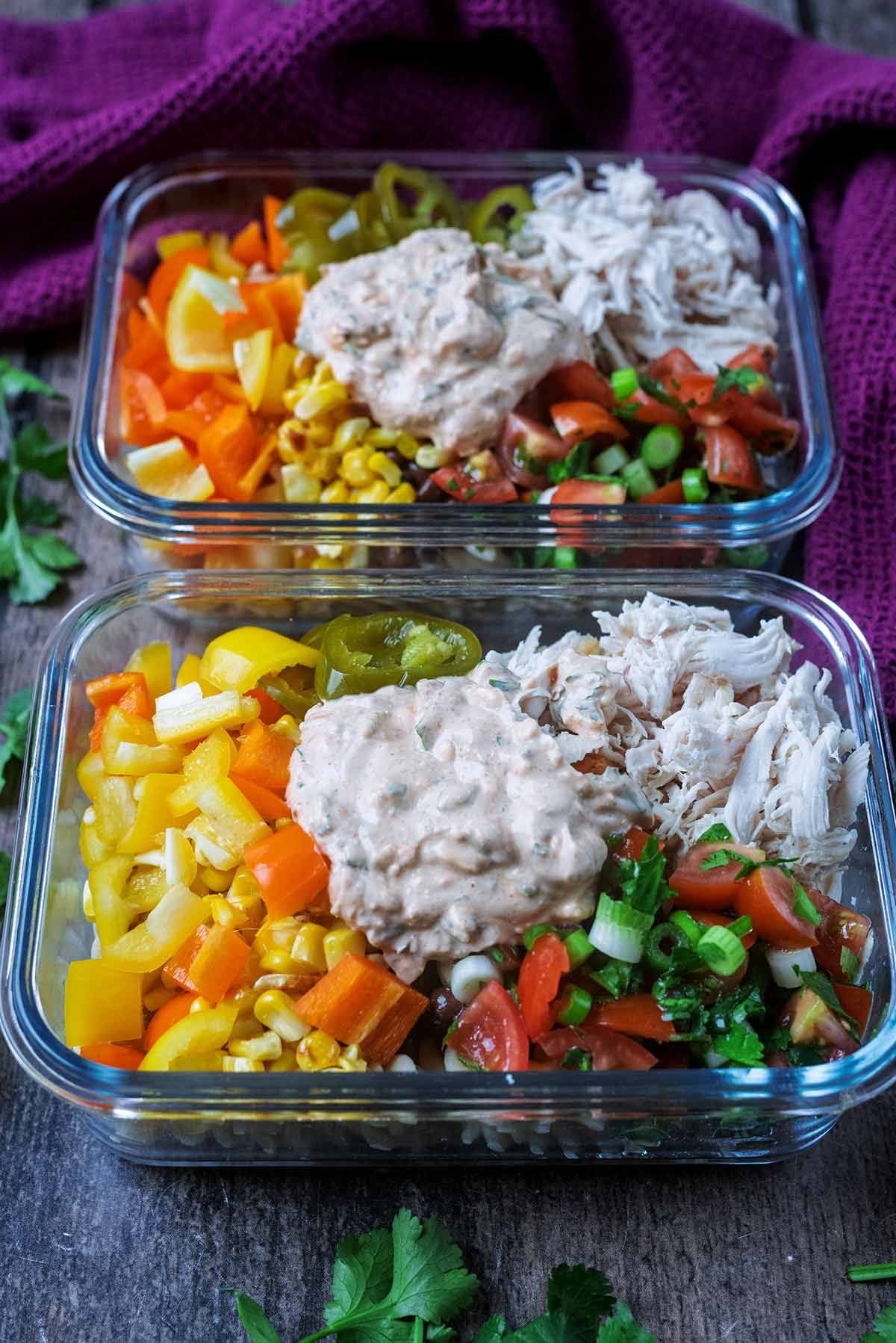 Two glass containers, in in front of the other, with pasta salads in them.